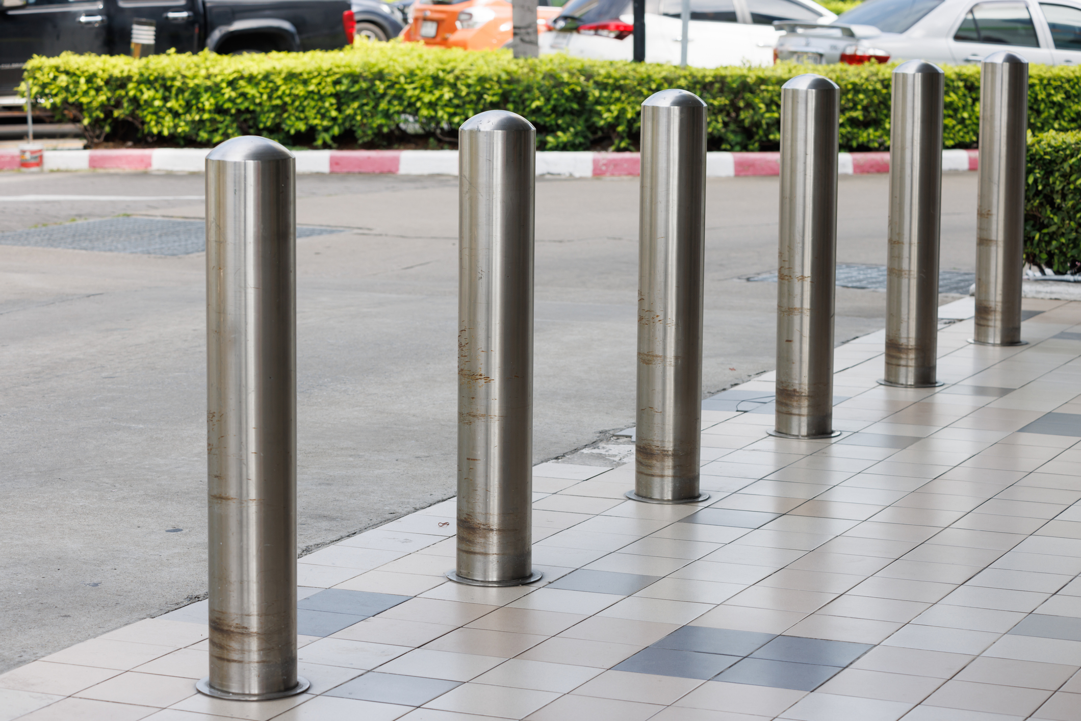 stainless steel bollards on footpath walkway near car park lot.